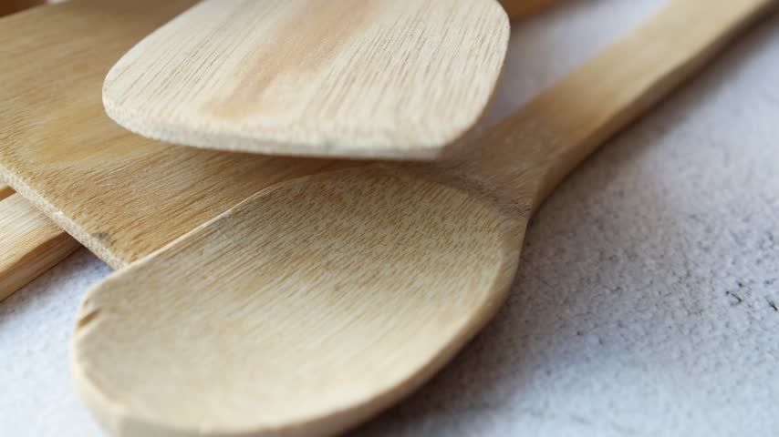 Wooden spoons and spatulas arranged neatly on a white textured background. Close-up view of natural kitchenware.