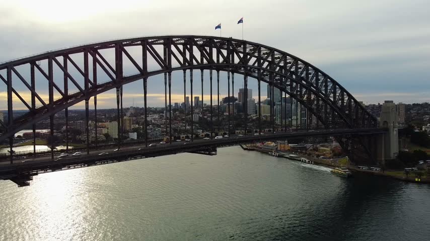 Aerial view of the iconic Sydney Harbour Bridge spanning the harbour with city skyline and water below in Sydney, New South Wales, Australia.