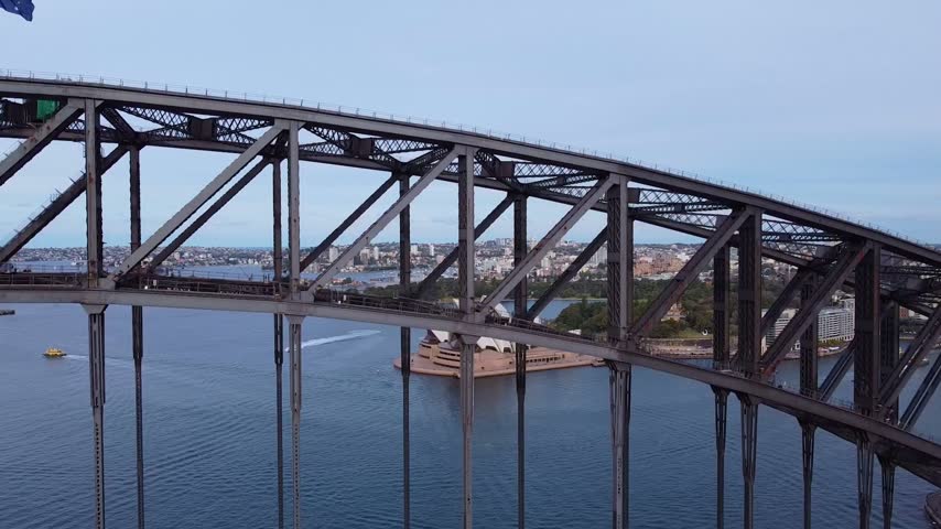 Aerial view of Sydney Harbour Bridge with the Sydney Opera House in the background and boats on the water in Sydney, New South Wales, Australia.