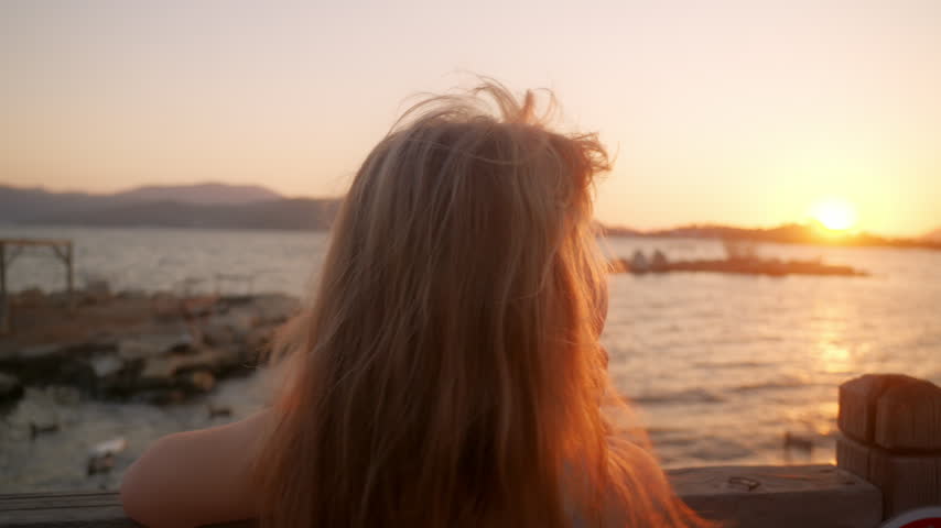 Sunset view over water with a child girl looking at the horizon in a lakeside setting during evening hours