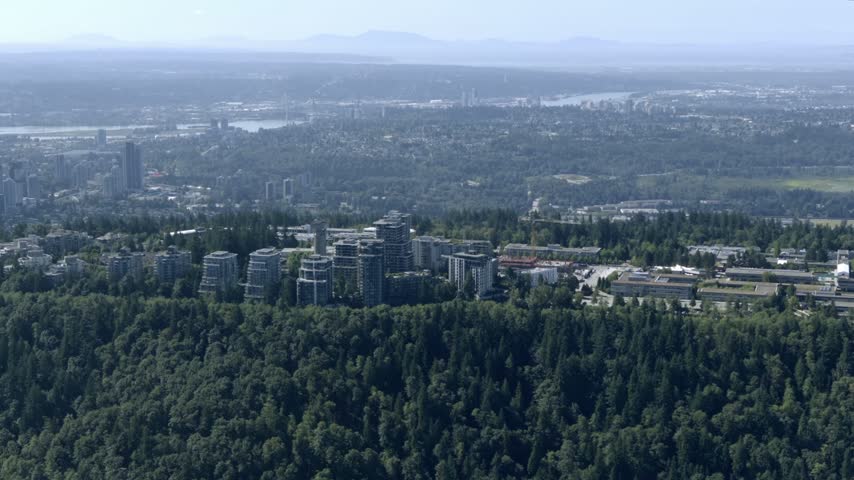 Simon Fraser University Campus And Residences Over Dense Forested Burnaby Mountain In Metro Vancouver, Canada. - aerial shot