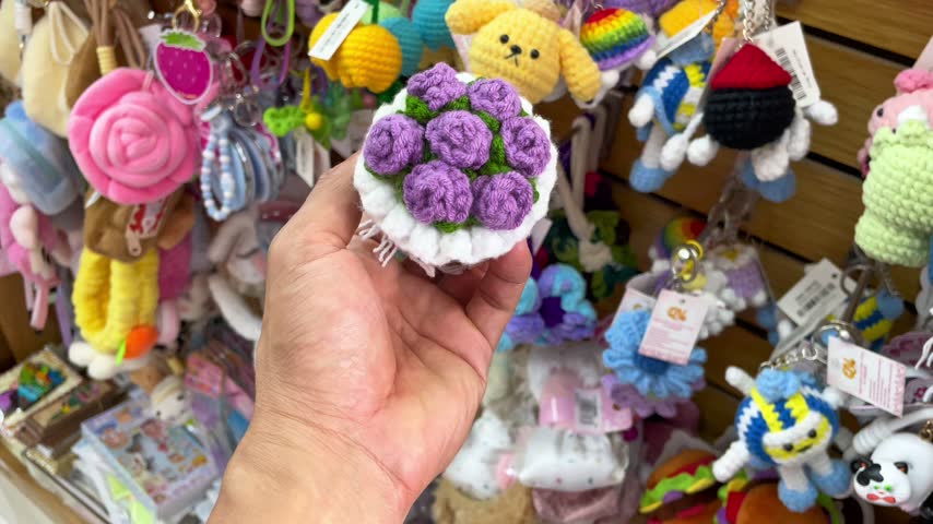 A handmade crochet purple flower bouquet ornament held in a person