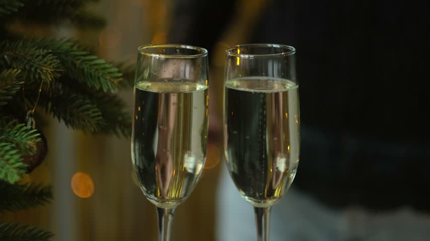 New year eve celebration, festive party. Woman taking two glasses of champagne or white sparkling wine from table