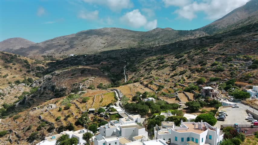 Aerial drone shot over a winding road and dry-stone terraces on an arid mountainside past the village of Langada near Aegiali on Amorgos, Cyclades, Greece, on a sunny day