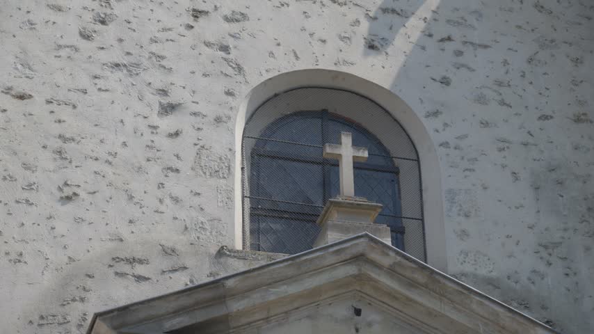 Low Angle View of Stone Cross and Arch Window on Historic French Church Facade
