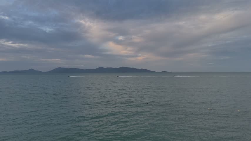 Aerial flight over the calm sea toward distant islands at dusk, Maenam, Koh Samui, Thailand