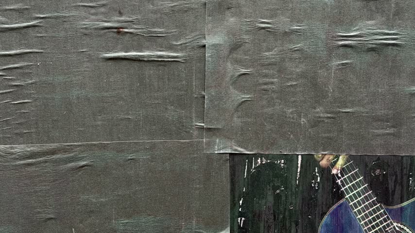 Close up view of a weathered urban wall with peeling layers of old, ripped paper posters