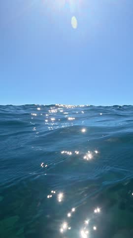 Sunlit ocean waves with distant clouds.