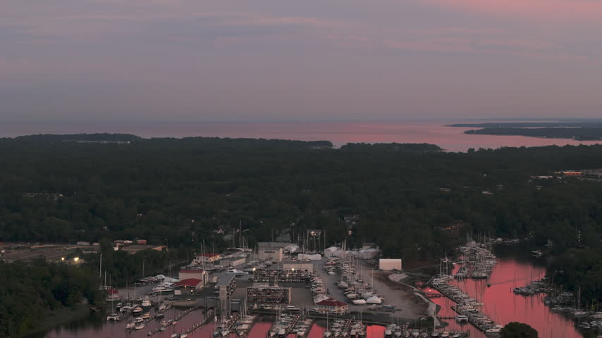 Annapolis Boat Basin, Waterfront Shipyard, Forested Shoreline, And Distant Waterways At Dusk In Maryland, USA. - aerial shot