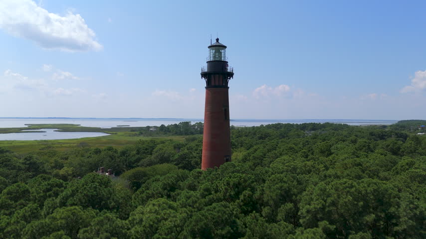 Red Brick Currituck Beach Lighthouse Above Dense Green Forest Canopy Near The Sound on Outer Banks, Corolla, USA.- aerial shot