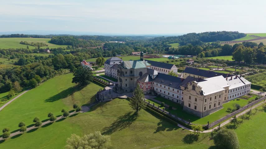 Aerial view of Hospital Kuks surrounded by lush green gardens and rolling hills in Kuks, Kralovehradecky kraj, Czechia.
