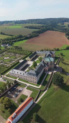 Aerial view of Hospital Kuks with its formal gardens, courtyard, and surrounding rural landscape in Kuks, Kralovehradecky kraj, Czechia.