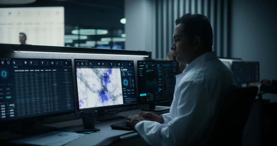 Scientific Medical Scientific Research Facility, Monitoring Control Room: Portrait of Male Scientist Working on Desktop Computer, Studying Mri Brain Scans. Specialist Uses Ai, Big Data Software