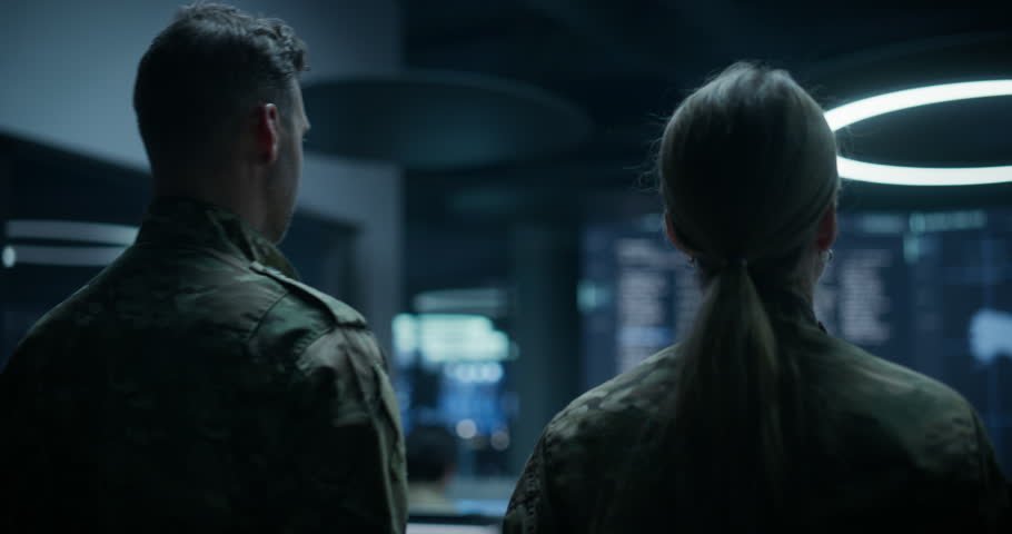 Army Military Surveillance Monitoring Control Room: Male and Female Officers in Uniform Hold a Briefing Meeting and Talk Near a Giant Satellite Map Wall, Pointing at Ai Analysis of Enemy Attack Routes