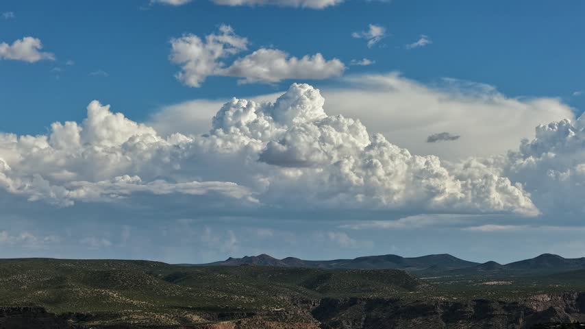 Aerial view of a large cumulus cloud formation rising like a pillar above the hilly canyon chaparral landscape in White Rock, New Mexico, United States.