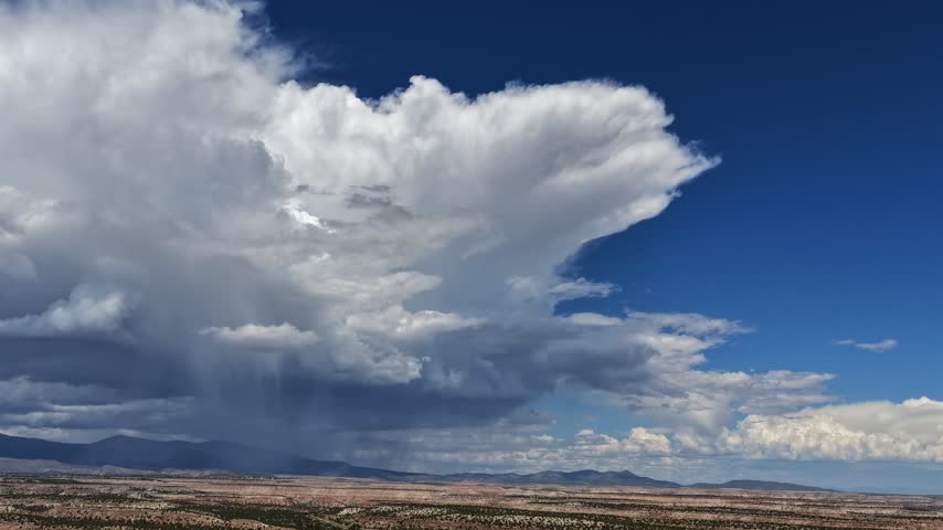 Aerial view of a large monsoon cloud formation raining over the arid mesa landscape in White Rock, New Mexico, United States.