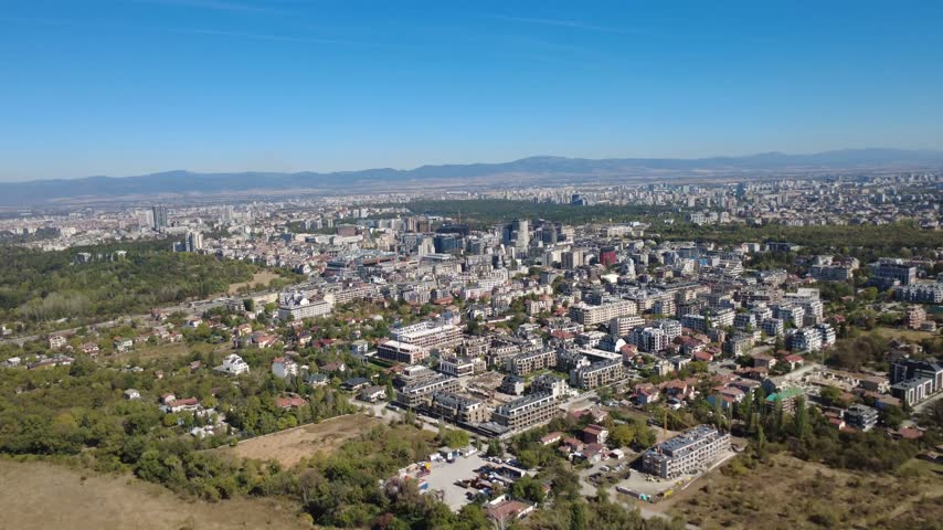 Aerial view of the cityscape of Sofia with modern buildings, residential areas, and green spaces under a clear blue sky in Sofia, Sofia City Province, Bulgaria.