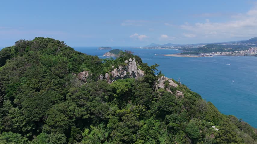Rocky Mountain Overlooking Seogwipo City Along The Southern Coast Of Jeju Island, South Korea. Aerial Drone Shot