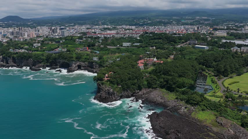 Dense Coastal Cityscape On Volcanic Cliffside Of Seogwipo On Jeju Island, South Korea. Aerial Drone Shot