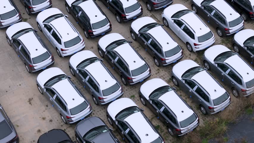 Aerial view of rows of new white and dark grey cars parked in an orderly lot in Gdansk, Poland.