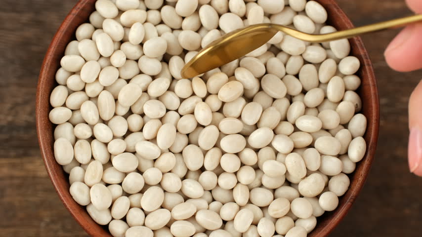 Pile white beans scooped with spoon from bowl, top view