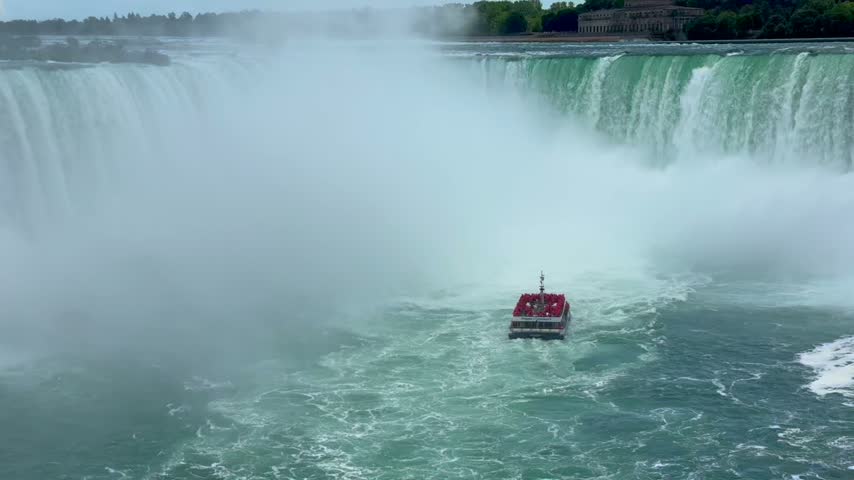 American and Horseshoe falls, Niagara Falls, Ontario, Canada. A boat navigates the waters near Niagara Falls, surrounded by mist and powerful cascades of water creating a stunning natural scene