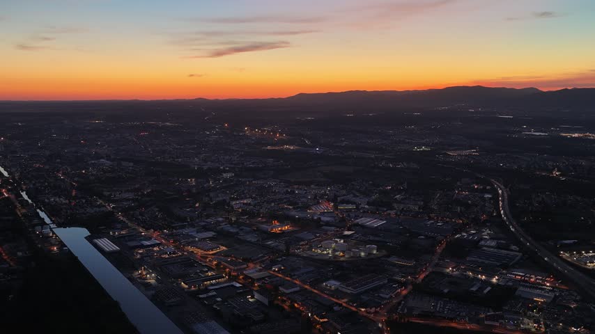 Aerial view of the city of Mulhouse at sunset with glowing street lights and urban landscape in Mulhouse, Grand Est, France.