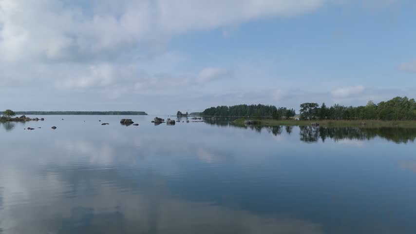 Aerial view of the calm waters of the Gulf of Finland with scattered rocks and forested coastline in Hamina, Kymenlaakso, Finland.