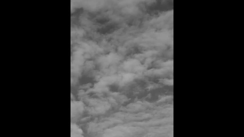 Clouds move slowly across the sky in the afternoon. The scene shows a variety of cloud shapes and shades. The light changes as the clouds pass.