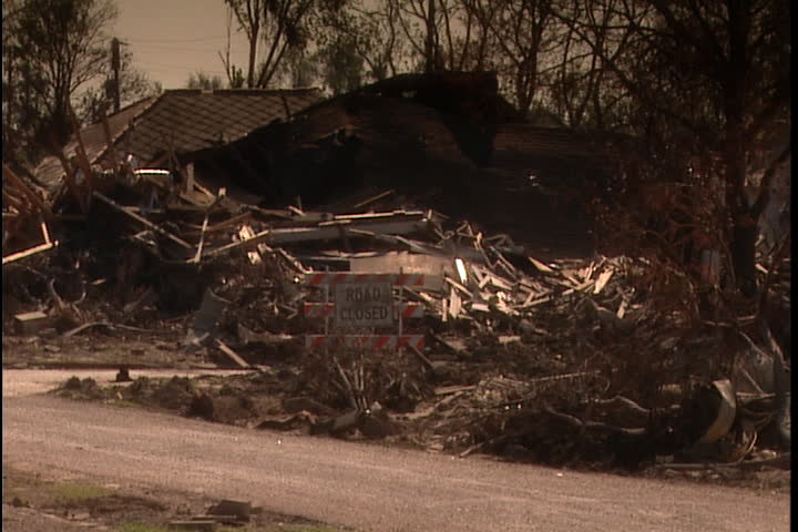 Remains of house and pile of rubble and boards. Camera pans across street to show rubble and overturned cars  in New Orleans after Hurricane Katrina (October 2005).