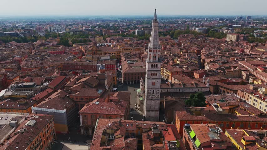 Aerial drone view of Modena Cathedral, Duomo di Modena, in Italy, showcasing its Romanesque architecture, historic rooftops, Piazza Grande, and the heart of Modena old town.