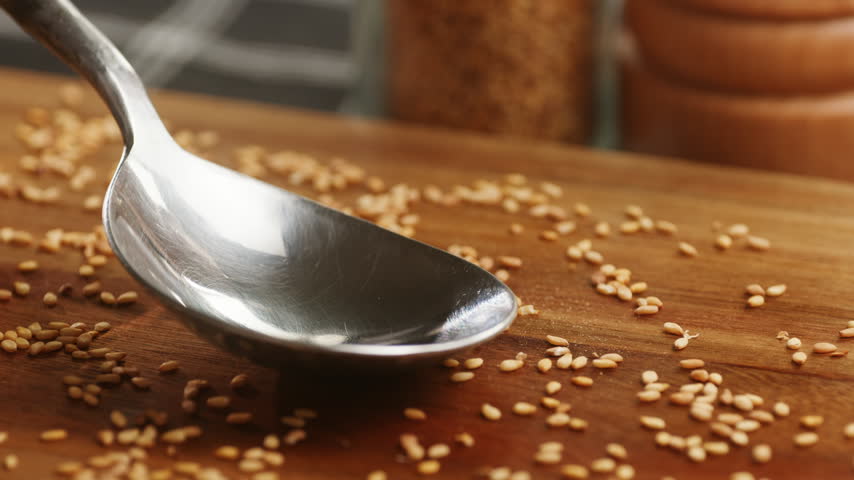 Linseed oil pouring into spoon, flaxseed oil with flax seeds on wooden table, healthy organic omega 3 superfood oil macro close up