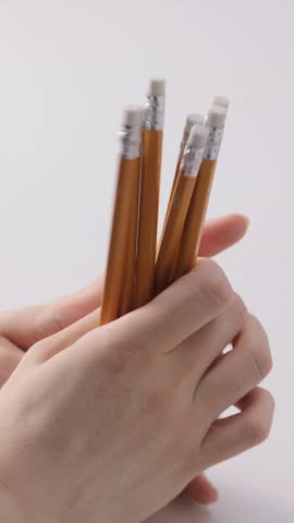 Hands gripping a cluster of yellow pencils on white background