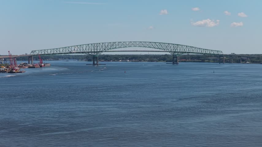 Aerial view of the Dames Point Bridge spanning the St Johns River with steel truss structure under a clear blue sky in Jacksonville, Florida, United States.
