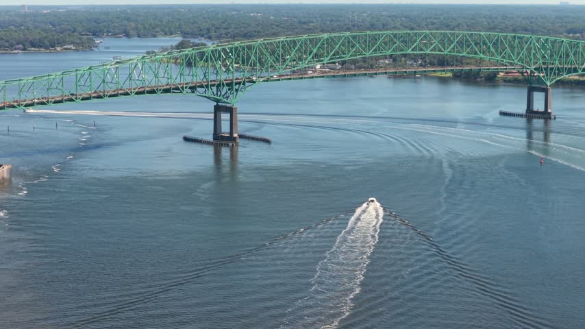 Aerial view of the Dames Point Bridge spanning the St. Johns River with a boat moving through the water in Jacksonville, Florida, United States.