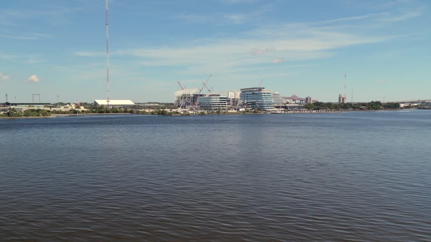 Aerial view of the Jacksonville skyline featuring modern buildings and construction cranes along the St. Johns River in Jacksonville, Florida, United States.