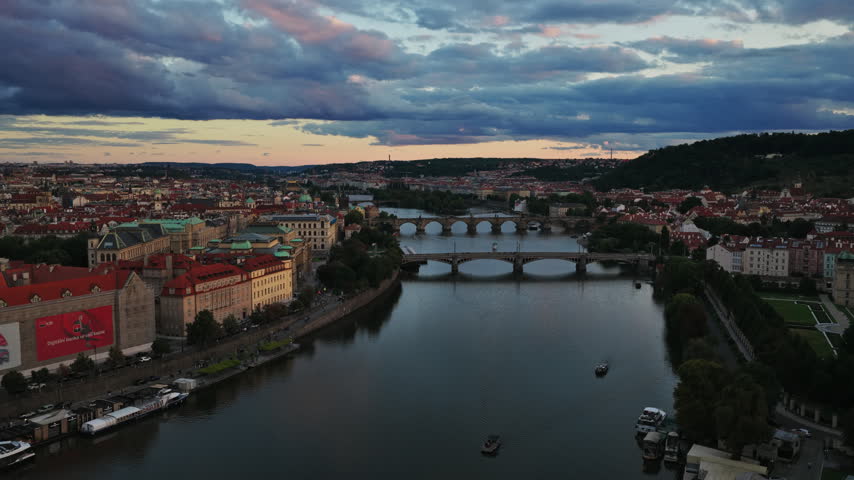 Arched Bridges Spanning Across The Vltava River Under A Dramatic Sunset Sky In Prague, Czech Republic. - aerial shot