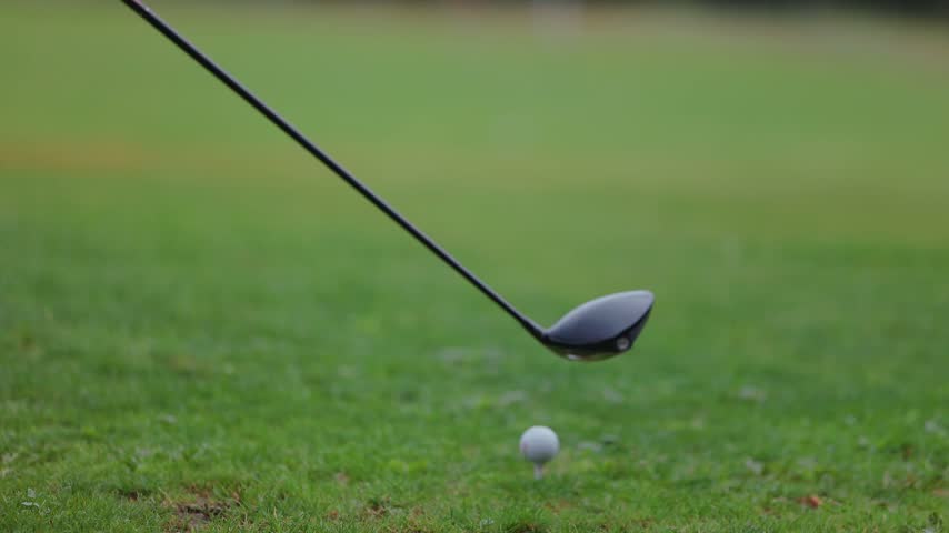 Golf club driver rests on short grass while a close view reveals its dark clubhead and shaft at an outdoor course in daylight