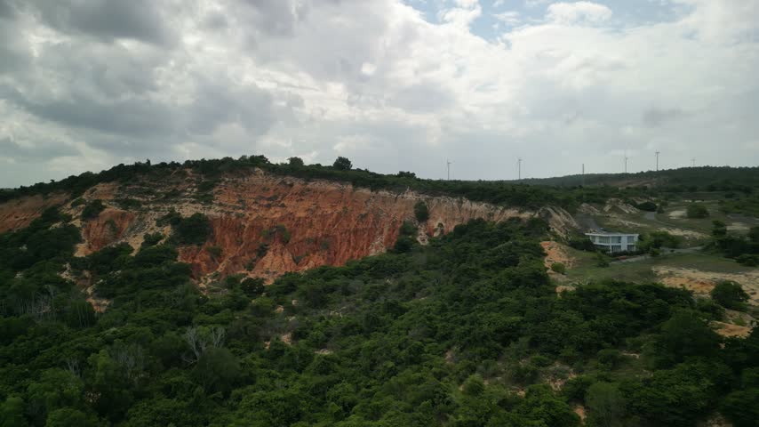 Aerial View of Red Clay Cliffside with Lush Green Vegetation