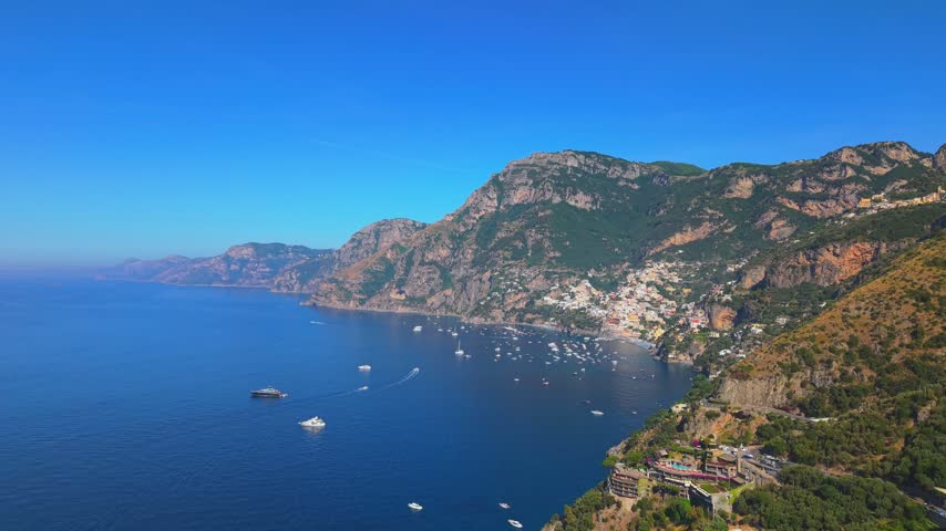 Romantic couple standing on a road bridge leaning over the railing to view the turquoise waters and cliffs of Fiordo di Furore.