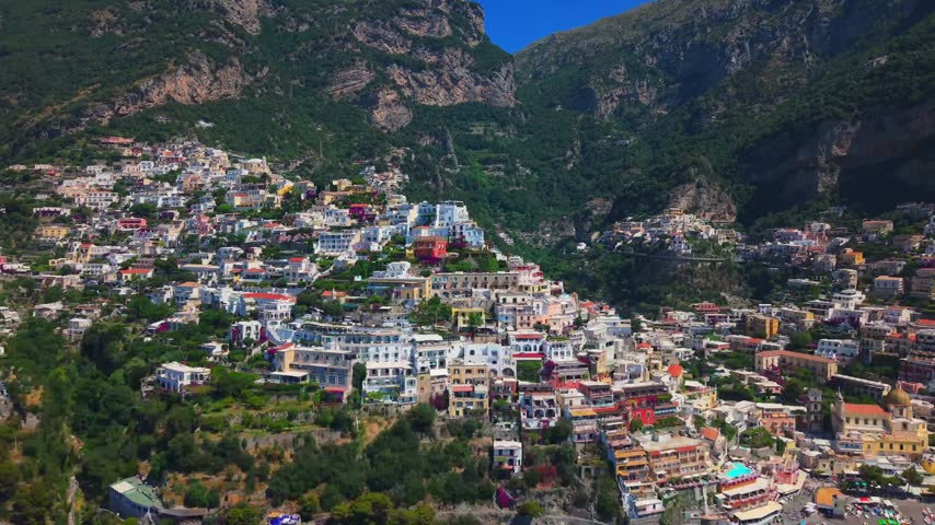 Iconic view of Positano village in Campania, Italy, nestled between steep mountain cliffs and deep blue sea.