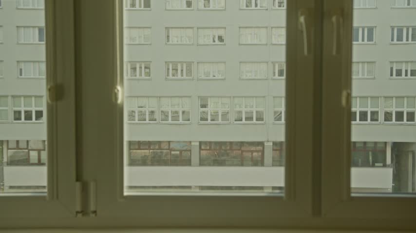 Poland, Wroclaw 2023 01 14: Interior view looking through a closed window at a large urban apartment building facade across the street, horizontal shot.