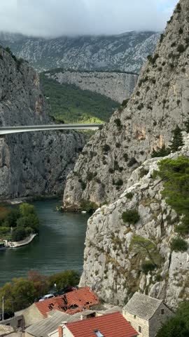 Narrow canyon landscape with steep rocky cliffs and lush green trees along a winding river near Omiš under dramatic clouds, nature tourism, outdoor adventure, adventure travel, river canyon, scenic landscape, natural beauty, dramatic mountains, wildlife.