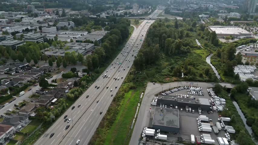 Aerial View Of Cars Driving Through Highway Along Suburban Houses And Creek In BC, Canada.