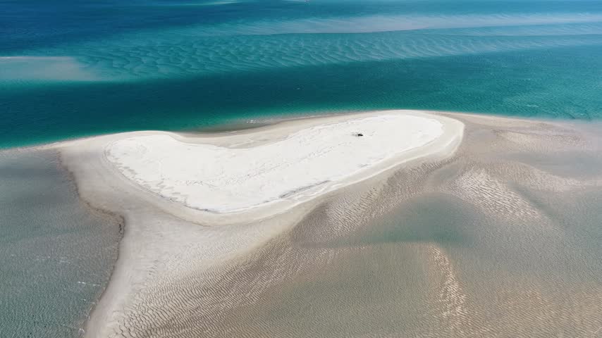 Aerial view of a white sandbar surrounded by turquoise water with ripples in the sand at Amity Point, Queensland, Australia.