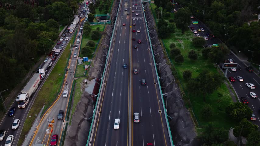 Aerial view of heavy traffic on a multi-lane highway surrounded by green trees in Mexico City, Mexico City, Mexico.