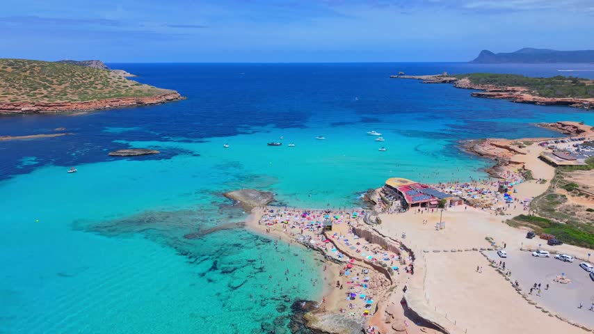 High-angle perspective of Ibiza coastline showcasing crystal-clear blue waters and scenic islets.
