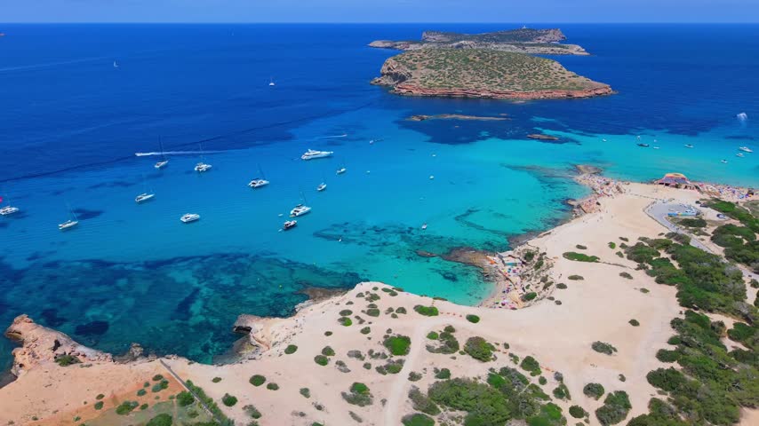 Aerial view of Mediterranean coastal waters meeting rocky shores and sandy beaches in Ibiza.