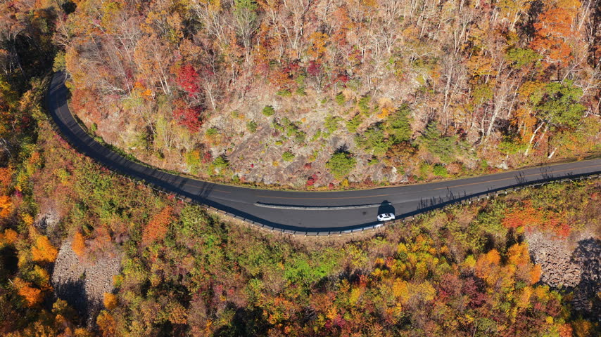 Autumn landscape in Appalachian Mountains of Tennessee featuring parked car at roadside overlook with panoramic forest views.