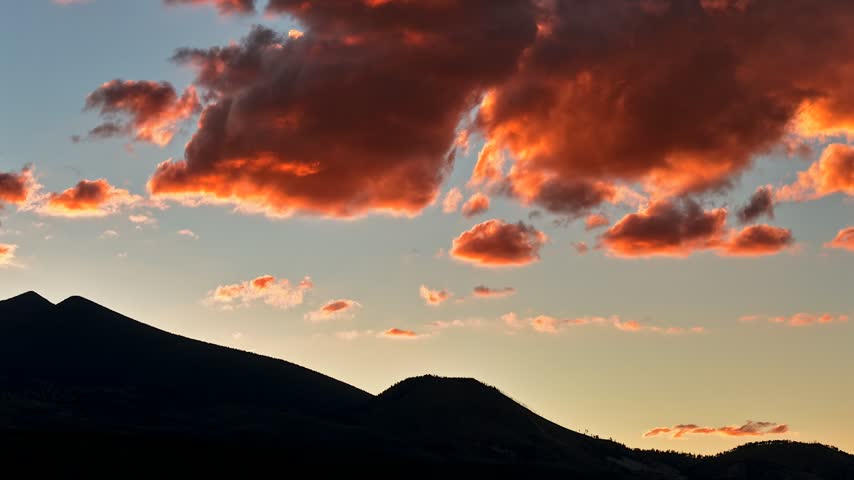 Aerial view of vibrant sunset clouds drifting over the San Francisco Peaks in Flagstaff, Arizona, United States.